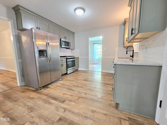 112 Saddletree Rd, Oxford, NC 27565 - kitchen featuring appliances with stainless steel finishes, light wood-type flooring, tasteful backsplash, and gray cabinetry