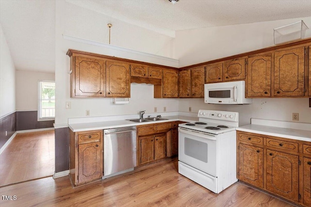 34 Scotts Creek Run, Angier, NC 27501 - kitchen with white appliances, lofted ceiling, brown cabinetry, light wood-style floors, and light countertops