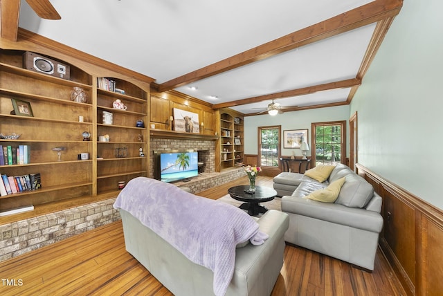 821 Ascot Ln, Raleigh, NC 27615 - living room with ceiling fan, beamed ceiling, a wainscoted wall, a fireplace, and hardwood / wood-style flooring