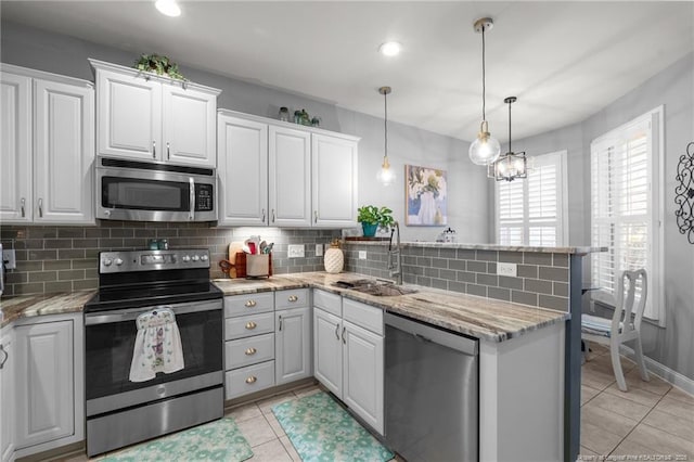 82 Pine Hawk Dr, Spring Lake, NC 28390 - kitchen with appliances with stainless steel finishes, a peninsula, light tile patterned floors, decorative backsplash, and white cabinetry