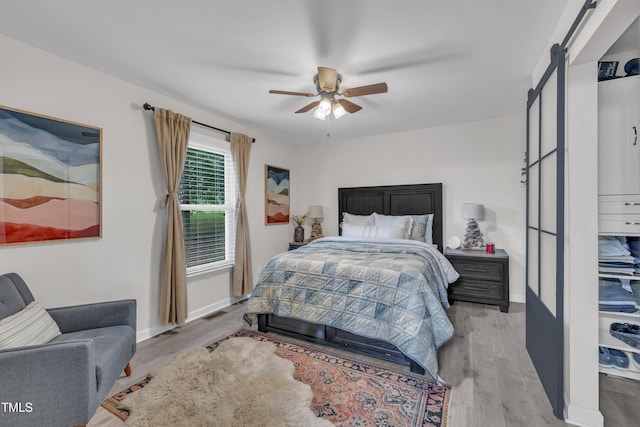 8801 Valley Hill Ct, Apex, NC 27539 - bedroom featuring wood finished floors, a barn door, and a ceiling fan