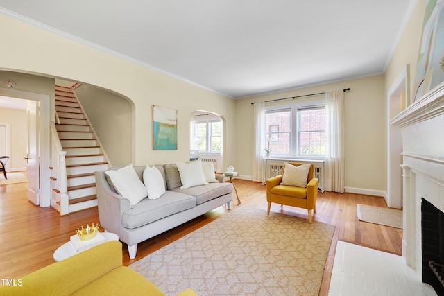 1007 W Markham Ave, Durham, NC 27701 - living area featuring crown molding, arched walkways, a fireplace with flush hearth, light wood-style floors, and stairs