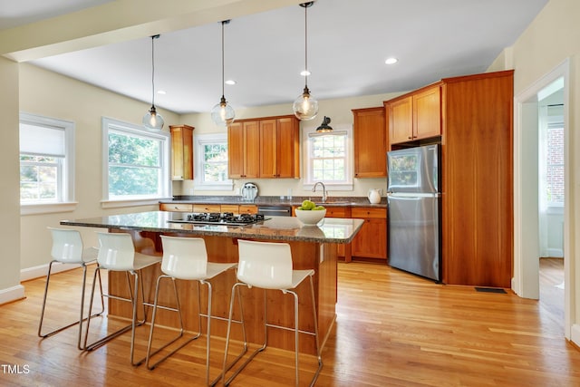 1007 W Markham Ave, Durham, NC 27701 - kitchen with stainless steel appliances, light wood-style flooring, brown cabinets, a breakfast bar, and recessed lighting