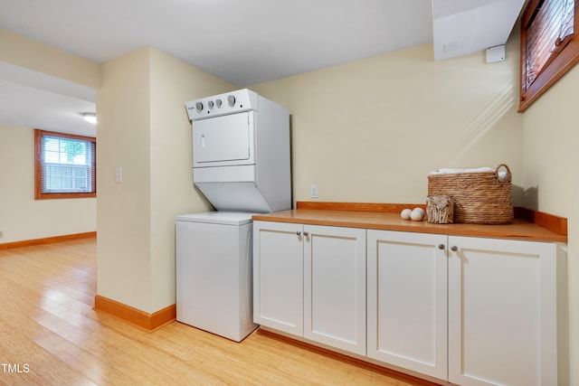 1007 W Markham Ave, Durham, NC 27701 - laundry room featuring estacked washer and dryer, light wood-style floors, and cabinet space