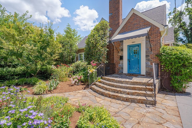 1007 W Markham Ave, Durham, NC 27701 - doorway to property featuring brick siding, a shingled roof, and a chimney