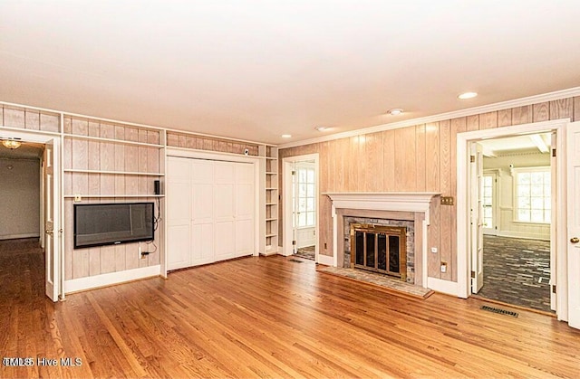322 Gravley Dr, Rocky Mount, NC 27804 - unfurnished living room featuring a glass covered fireplace, ornamental molding, wood finished floors, built in features, and wooden walls