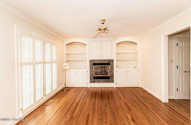 322 Gravley Dr, Rocky Mount, NC 27804 - unfurnished living room with wood finished floors, a tiled fireplace, built in features, a ceiling fan, and crown molding