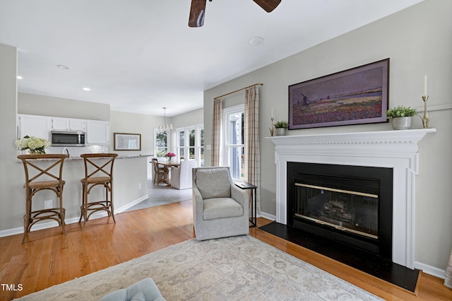 8841 Deerland Grove Dr, Raleigh, NC 27615 - living room featuring light wood-style floors, a ceiling fan, a glass covered fireplace, and recessed lighting