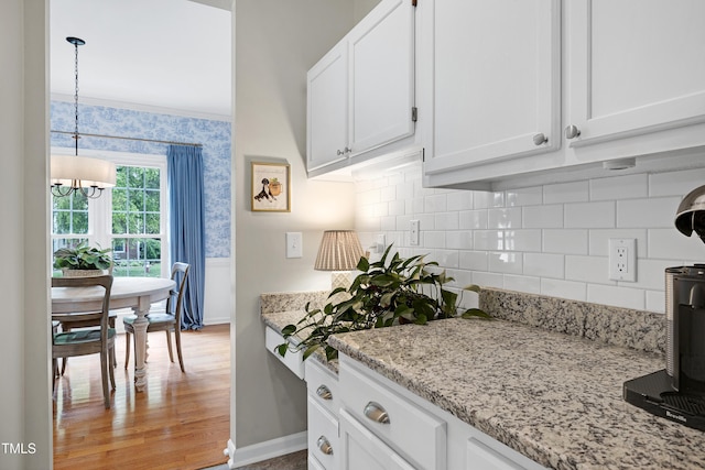 8841 Deerland Grove Dr, Raleigh, NC 27615 - kitchen with white cabinetry, a chandelier, tasteful backsplash, and wallpapered walls