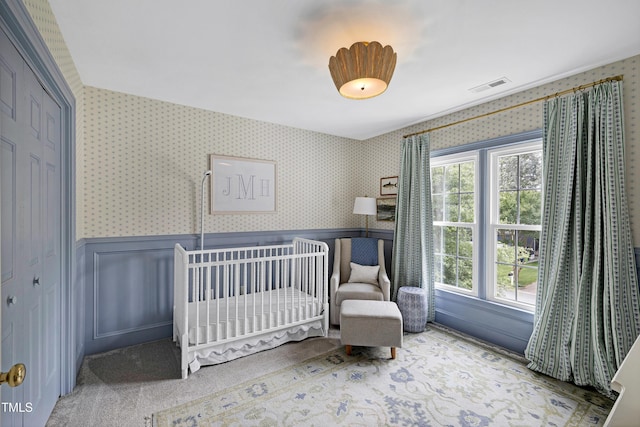 8841 Deerland Grove Dr, Raleigh, NC 27615 - carpeted bedroom with wallpapered walls, a wainscoted wall, a closet, and a crib