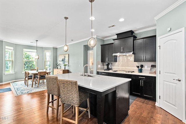 1523 Anthology Dr, Durham, NC 27703 - kitchen with stainless steel gas stovetop, dark cabinetry, light countertops, tasteful backsplash, and under cabinet range hood