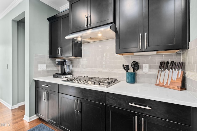 1523 Anthology Dr, Durham, NC 27703 - kitchen with stainless steel gas stovetop, under cabinet range hood, dark cabinets, crown molding, and light wood finished floors