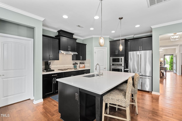 1523 Anthology Dr, Durham, NC 27703 - kitchen with stainless steel appliances, dark cabinetry, crown molding, under cabinet range hood, and decorative backsplash