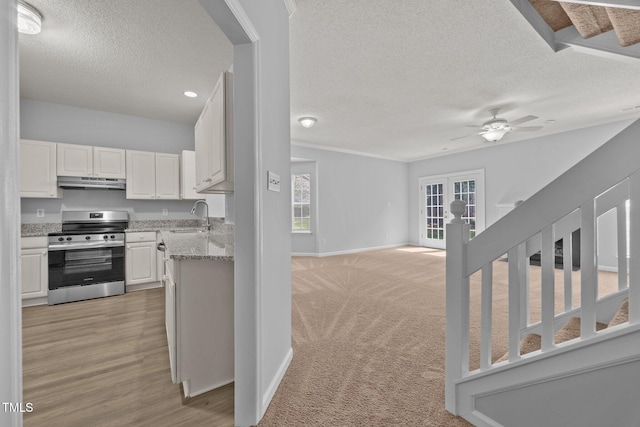 4406 Still Pines Dr, Raleigh, NC 27613 - kitchen with stainless steel stove, under cabinet range hood, a textured ceiling, white cabinetry, and a ceiling fan