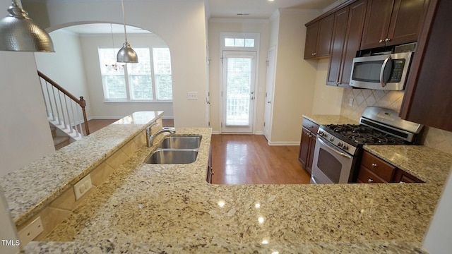 5916 Longeria Ct, Raleigh, NC 27612 - kitchen featuring stainless steel appliances, light stone countertops, tasteful backsplash, ornamental molding, and arched walkways