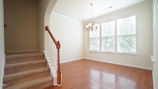 5916 Longeria Ct, Raleigh, NC 27612 - staircase featuring wood finished floors, crown molding, a chandelier, and arched walkways