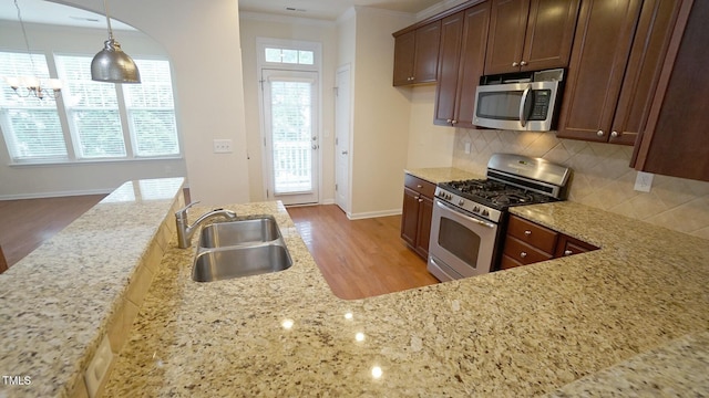5916 Longeria Ct, Raleigh, NC 27612 - kitchen with stainless steel appliances, backsplash, light stone counters, wood finished floors, and ornamental molding