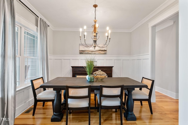 532 Joe Collins Rd, Lillington, NC 27546 - dining space with a chandelier, light wood-style floors, a decorative wall, a wainscoted wall, and ornamental molding