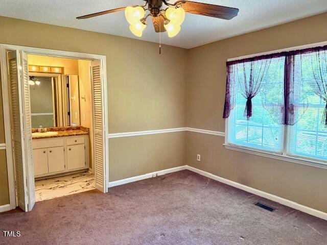 120 W Front St, Oxford, NC 27565 - unfurnished bedroom featuring multiple windows, carpet, ensuite bath, and ceiling fan