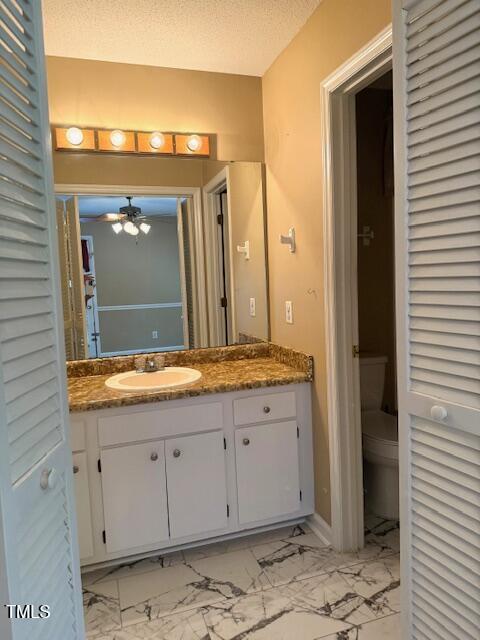 120 W Front St, Oxford, NC 27565 - bathroom featuring vanity, marble look tiles, a textured ceiling, and a ceiling fan