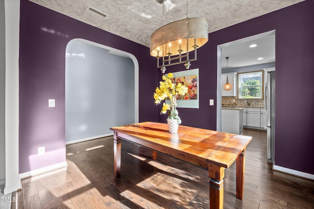 7 Faircroft Ct, Durham, NC 27703 - dining area featuring arched walkways, dark wood finished floors, and a chandelier
