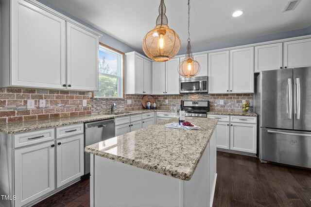 7 Faircroft Ct, Durham, NC 27703 - kitchen featuring appliances with stainless steel finishes, white cabinets, dark wood-style floors, a kitchen island, and decorative light fixtures