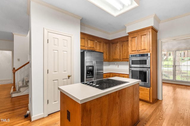 101 Turnberry Ln, Cary, NC 27511 - kitchen with stainless steel appliances, ornamental molding, light wood-style flooring, brown cabinetry, and light countertops