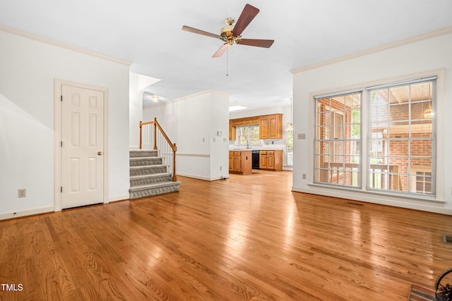 101 Turnberry Ln, Cary, NC 27511 - unfurnished living room featuring stairs, light wood-style flooring, crown molding, and a ceiling fan