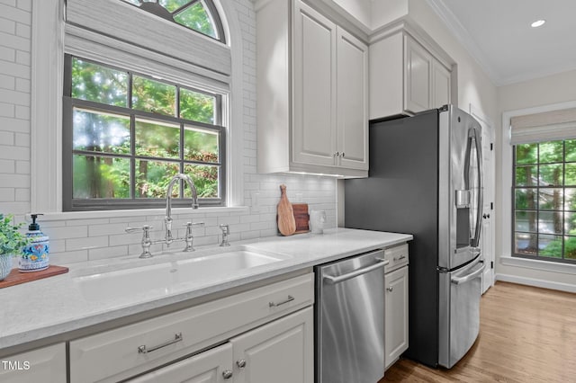 901 Tamaras Cir, Wake Forest, NC 27587 - kitchen with appliances with stainless steel finishes, white cabinetry, tasteful backsplash, ornamental molding, and light wood-style flooring