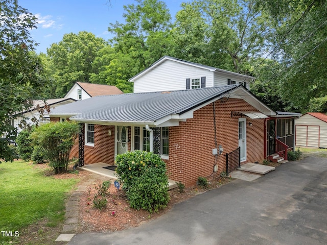 110 Starlite Dr, Carrboro, NC 27510 - view of front of property with entry steps, brick siding, a metal roof, asphalt driveway, and an outbuilding