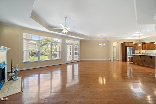 102 Mikaila Dr, Gibsonville, NC 27249 - unfurnished living room with a tray ceiling, ceiling fan, crown molding, a fireplace, and a chandelier
