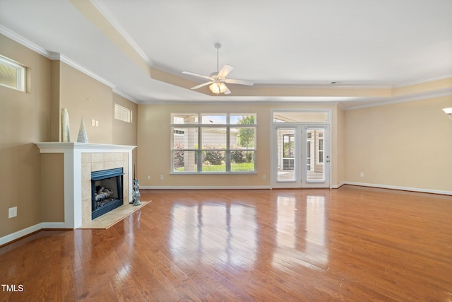 102 Mikaila Dr, Gibsonville, NC 27249 - unfurnished living room with ceiling fan, ornamental molding, wood finished floors, a tile fireplace, and a tray ceiling