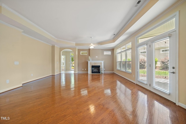 102 Mikaila Dr, Gibsonville, NC 27249 - unfurnished living room with a raised ceiling, ceiling fan, arched walkways, wood finished floors, and a tiled fireplace