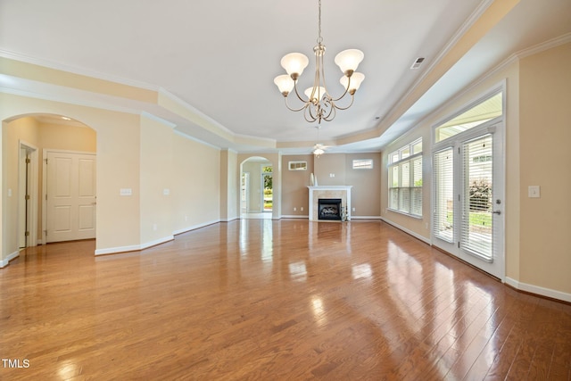 102 Mikaila Dr, Gibsonville, NC 27249 - unfurnished living room featuring arched walkways, a chandelier, light wood finished floors, a raised ceiling, and a tile fireplace