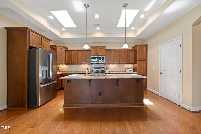 102 Mikaila Dr, Gibsonville, NC 27249 - kitchen featuring stainless steel appliances, a skylight, a tray ceiling, brown cabinets, and wood finished floors