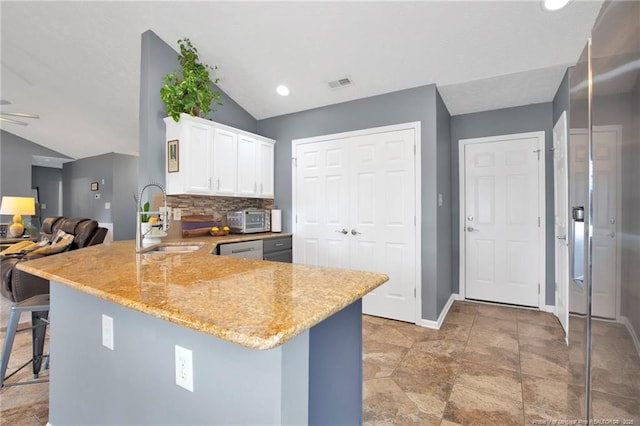 420 Gibson Dr, Raeford, NC 28376 - kitchen with vaulted ceiling, light stone countertops, a peninsula, white cabinetry, and backsplash