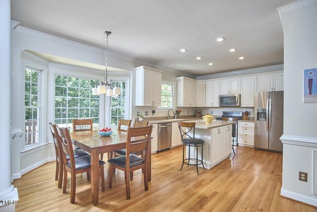 5328 Willow Cry Ln, Raleigh, NC 27613 - kitchen with stainless steel appliances, light wood-style flooring, ornamental molding, a breakfast bar, and a center island