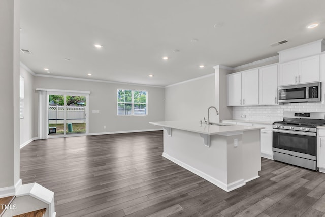 6549 Tremolo Trl, Raleigh, NC 27616 - kitchen featuring appliances with stainless steel finishes, ornamental molding, open floor plan, a center island with sink, and dark wood-style floors