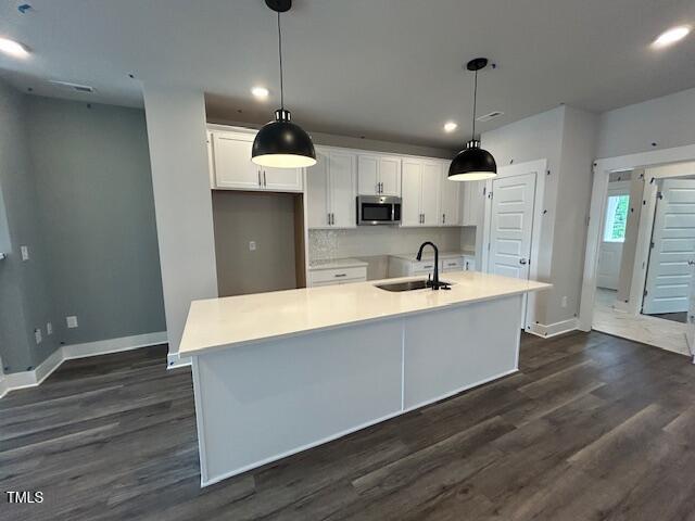 502 Yeowell Dr, Chapel Hill, NC 27514 - kitchen featuring stainless steel microwave, white cabinetry, recessed lighting, dark wood-type flooring, and an island with sink