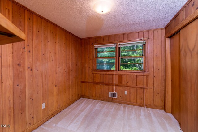 452 N Main St, Wendell, NC 27591 - unfurnished bedroom with wood walls, a textured ceiling, a closet, and light carpet