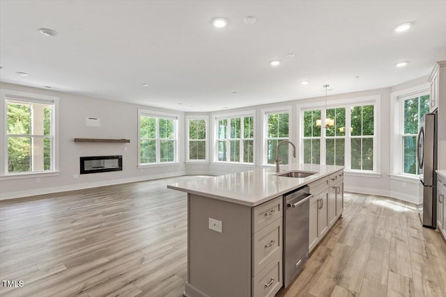 11548 Helmond Way # 104, Raleigh, NC 27617 - kitchen with stainless steel appliances, a center island with sink, light countertops, light wood-style flooring, and healthy amount of natural light