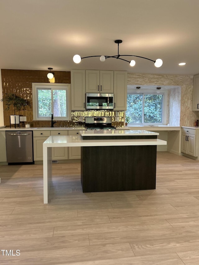 4812 Latimer Rd, Raleigh, NC 27609 - kitchen featuring appliances with stainless steel finishes, a chandelier, decorative backsplash, light countertops, and a center island