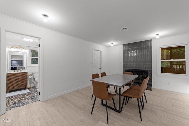 4812 Latimer Rd, Raleigh, NC 27609 - dining space with crown molding, light wood-type flooring, a fireplace, and plenty of natural light