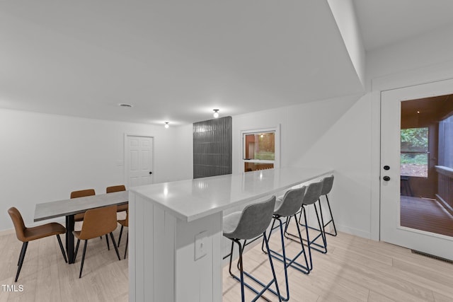 4812 Latimer Rd, Raleigh, NC 27609 - kitchen with a breakfast bar, a peninsula, light countertops, and light wood-style floors