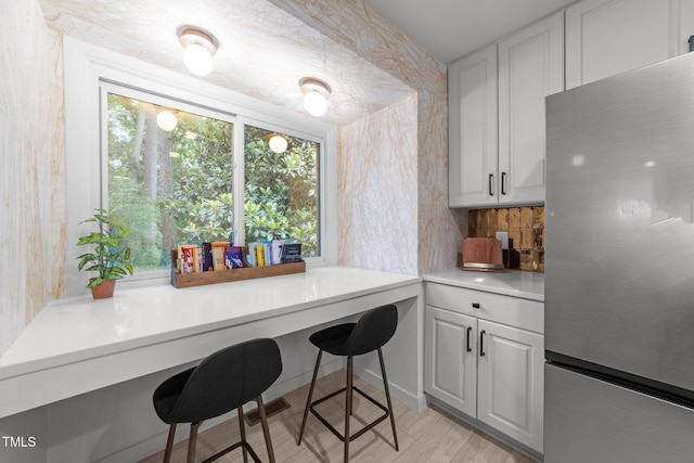 4812 Latimer Rd, Raleigh, NC 27609 - kitchen with freestanding refrigerator, light countertops, decorative backsplash, white cabinets, and a breakfast bar