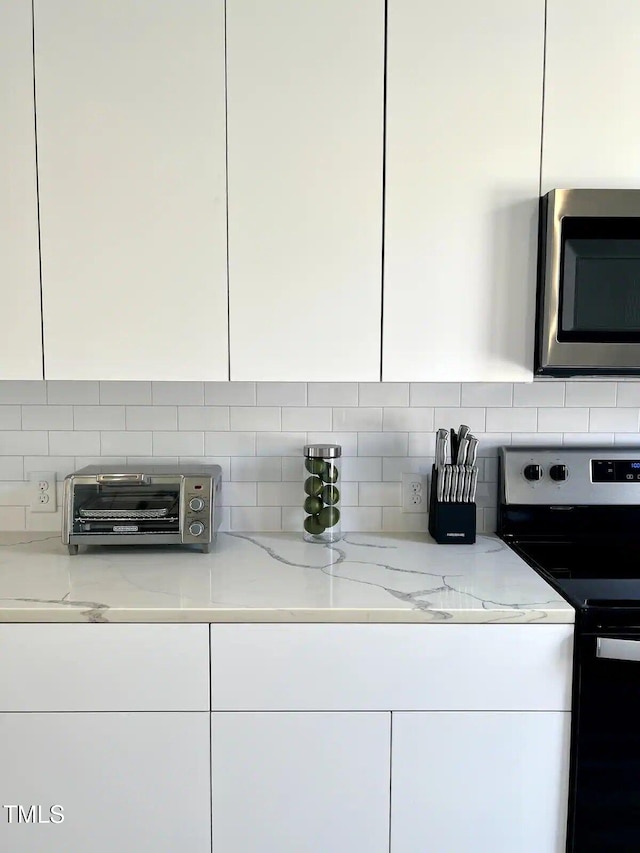 1106 Nova St, Durham, NC 27713 - kitchen featuring appliances with stainless steel finishes, white cabinets, backsplash, and light stone countertops