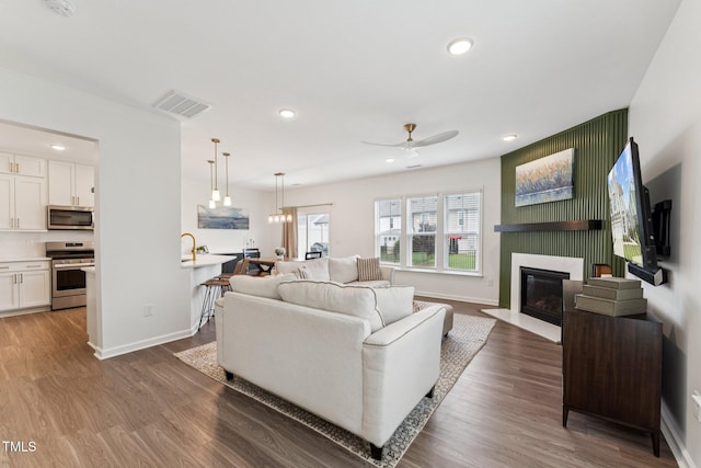 3194 Retama Run, New Hill, NC 27562 - living room featuring a ceiling fan, dark wood-style floors, a fireplace with flush hearth, and recessed lighting