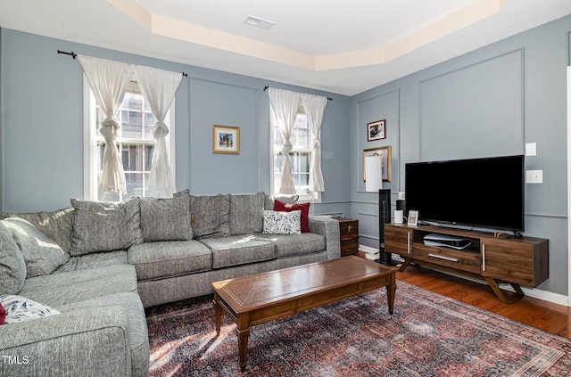 513 Dragby Ln, Raleigh, NC 27603 - living room featuring a tray ceiling, healthy amount of natural light, and wood finished floors