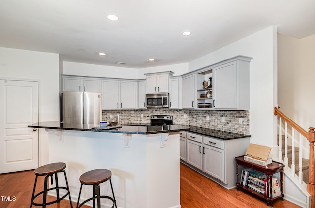 513 Dragby Ln, Raleigh, NC 27603 - kitchen with stainless steel appliances, open shelves, wood finished floors, a kitchen bar, and recessed lighting