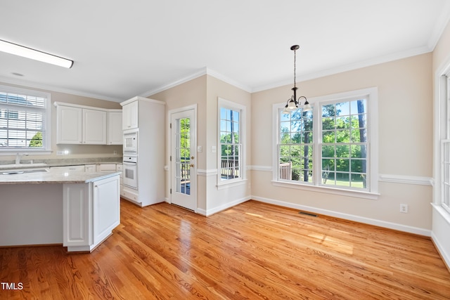 306 Neuse Ridge Dr, Clayton, NC 27527 - kitchen featuring light wood finished floors, white cabinets, plenty of natural light, and ornamental molding